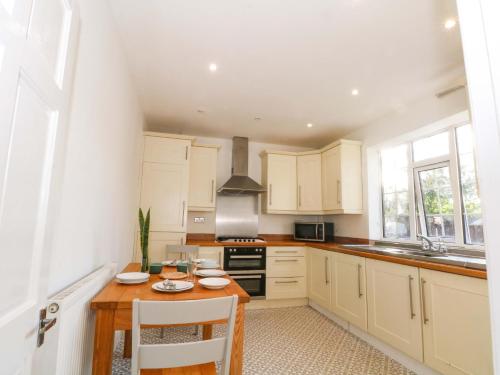 a kitchen with white cabinets and a wooden table at Ash House in Altrincham