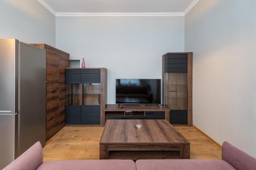 a living room with a table and a refrigerator at Elegant city center apartment with free parking by Polo Aparments in Kaunas