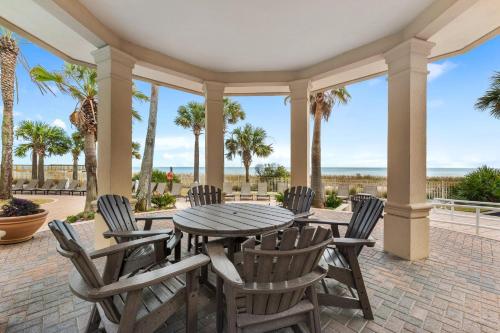a patio with a table and chairs and palm trees at Indigo East 1003 in Perdido Key