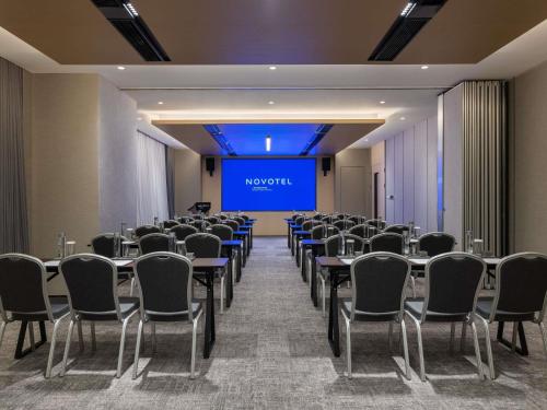 a conference room with tables and chairs and a projection screen at Novotel Shanghai Caohejing in Shanghai