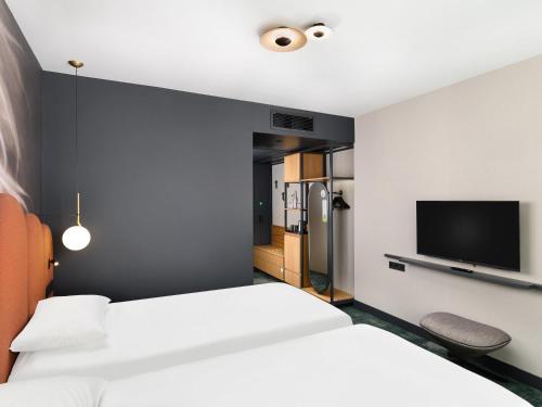 a hotel room with two beds and a tv at Mercure Debrecen in Debrecen