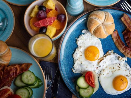 a table topped with plates of eggs and breakfast foods at Mercure Debrecen in Debrecen