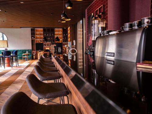 a row of chairs lined up in a bar at Mercure Debrecen in Debrecen