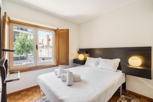 方The Sun and Sea Apartment by Minho's Guest的卧室里有一张白色的大床，床边有一扇窗户