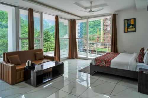 a bedroom with a bed and a couch and windows at The Nature's Nook - Best Stay in Shivpuri, Rishikesh, Hotel & Rooms in Shivpuri