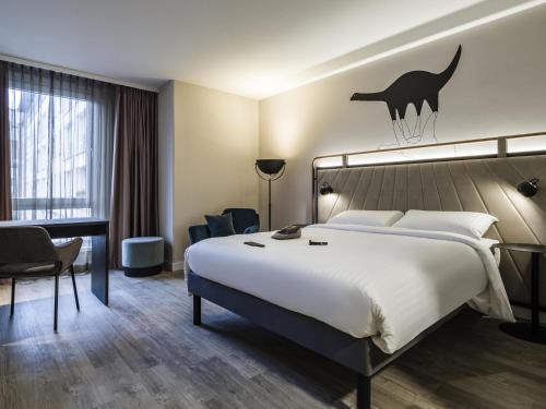 a hotel room with a large bed and a desk at ibis Styles Bielefeld City in Bielefeld