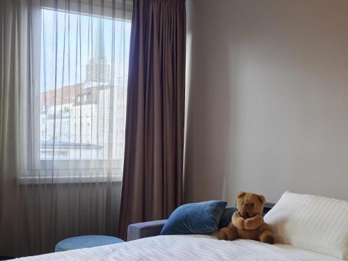 a teddy bear sitting on a bed in a hotel room at ibis Styles Bielefeld City in Bielefeld
