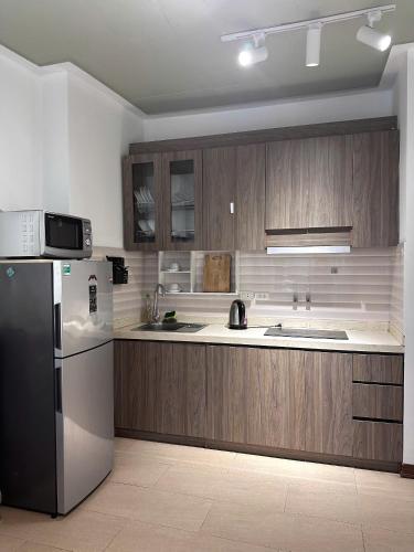 a kitchen with wooden cabinets and a stainless steel refrigerator at Tu Hoa Hotel by Luxe Hospitality in Hanoi