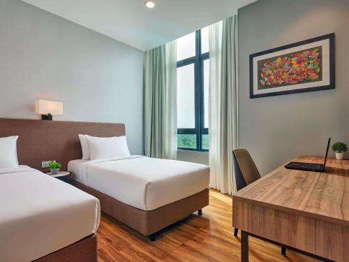 a hotel room with two beds and a desk and a table at Mercure Living Putrajaya in Putrajaya