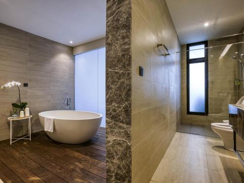 a bathroom with a tub and a shower and a sink at Mercure Living Putrajaya in Putrajaya
