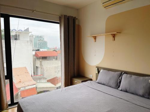 a bedroom with a bed and a large window at Tu Hoa Hotel by Luxe Hospitality in Hanoi