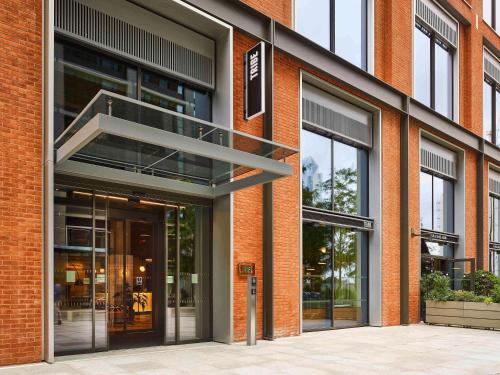 a red brick building with a revolving door at TRIBE London Canary Wharf in London