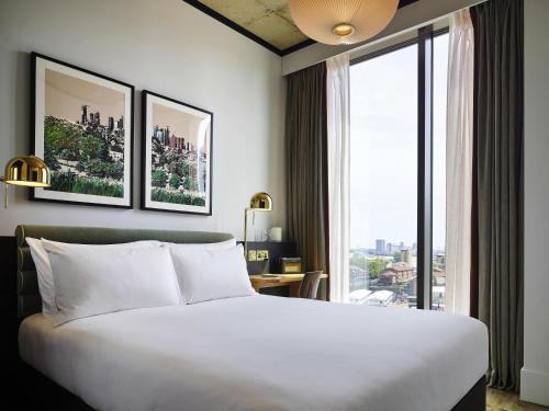 a hotel room with a bed and a large window at TRIBE London Canary Wharf in London