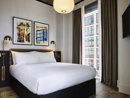 a bedroom with a large bed and a large window at TRIBE London Canary Wharf in London