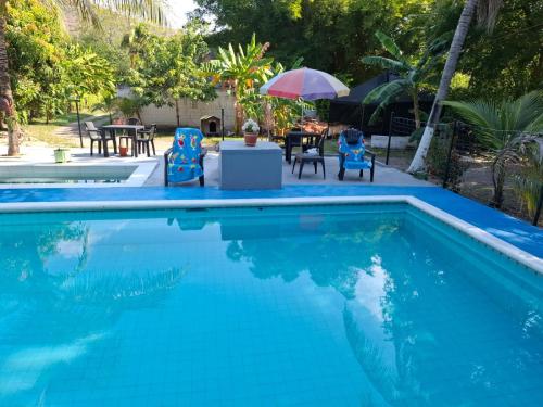 a swimming pool with chairs and a table and an umbrella at family home in Honda