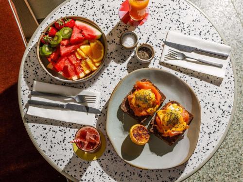 a table with a plate of food and a bowl of fruit at TRIBE London Canary Wharf in London