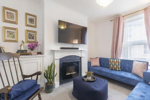 a living room with a blue couch and a fireplace at Central 3 Bedroom Home for 7 Guests in Cheltenham