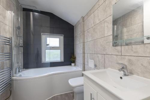 a white bathroom with a sink and a tub and a toilet at Central 3 Bedroom Home for 7 Guests in Cheltenham