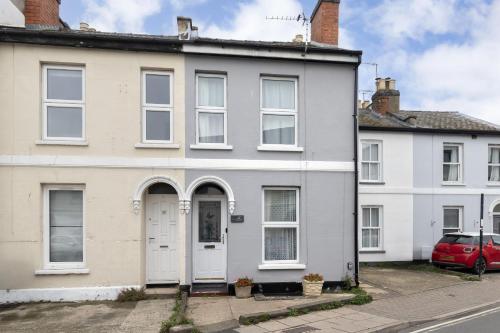 a white house with a red car parked in front at Central 3 Bedroom Home for 7 Guests in Cheltenham