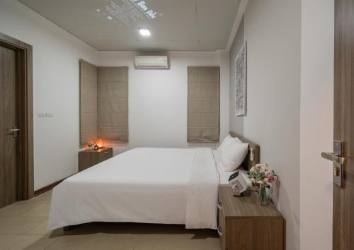 a bedroom with a white bed and a wooden table at Tu Hoa Hotel by Luxe Hospitality in Hanoi