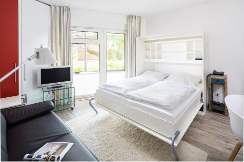 a white bedroom with a bed and a couch at Appartementhaus Bracht - Kleine Welle in Juist
