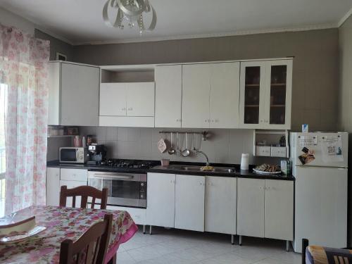 a kitchen with white cabinets and a table with a tableablish at HOME di Pia in Mugnano di Napoli
