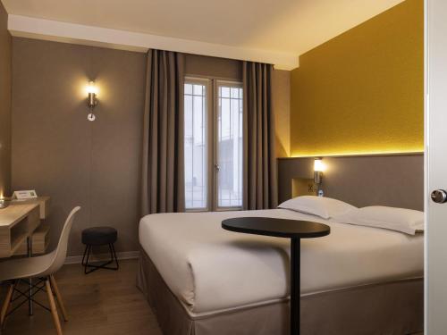 ブール・ラ・レーヌにあるibis Styles Bourg La Reineの大きなベッドとテーブルのあるホテルの部屋