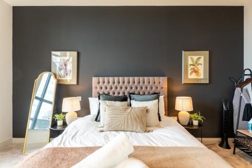 a bedroom with a large bed with two lamps and a mirror at Sleek 1BR City Stay - With Sofa Bed in Central Station