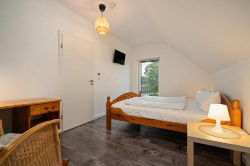 Un dormitorio con una cama y un escritorio y una ventana. en Ferienhaus VierSeen - Müritz, Fleesensee, Kölpinsee, Plauer See, en Walow