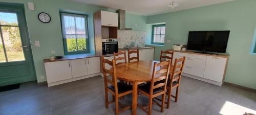 cocina con mesa y sillas y TV en Chez Jeannine - Maison 2kms plage, en Erquy