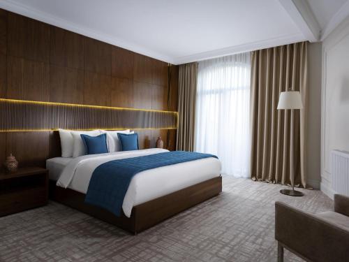 a hotel room with a large bed with blue pillows at Mercure Tashkent in Tashkent