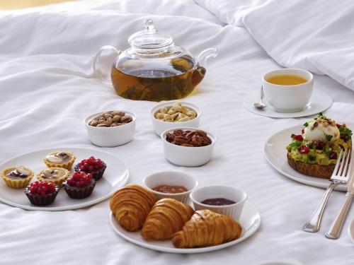 a table with plates of pastries and cups of tea at Mercure Tashkent in Tashkent