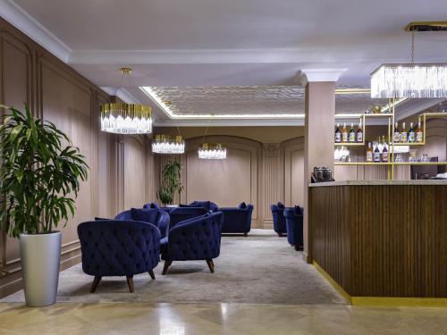 a dining room with blue chairs and a bar at Mercure Tashkent in Tashkent