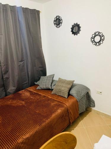 a bedroom with a bed with two clocks on the wall at Habitación en Sabaneta in Sabaneta