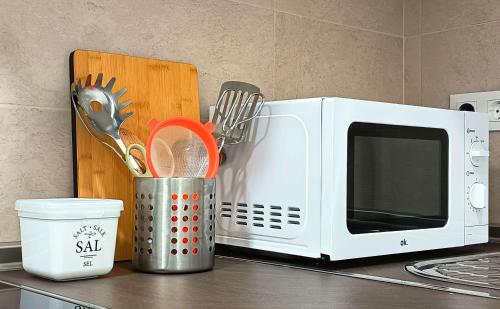 a kitchen counter with a microwave and a container of utensils at La Casita de Ale Casa Rural cerca Puy du Fou in Polán
