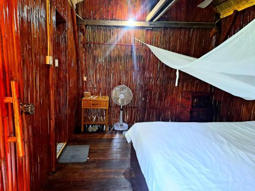 a bedroom with a bed and a fan in it at Savet Family Homestay & Tour in Battambang