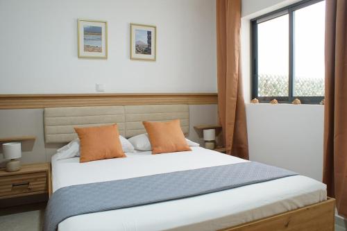 a bedroom with a large white bed with orange pillows at Sal Casa VILLAGE in Santa Maria