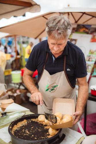 a man in a kitchen preparing food in a pan at Apartments - Turistična kmetija Vrbnjak in Ljutomer