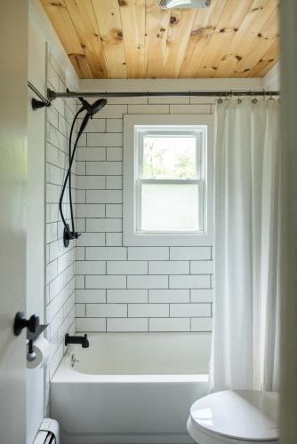a bathroom with a tub and a toilet and a window at Cozy Cottage in Glen Spey in Glen Spey