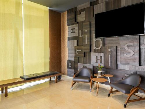 a living room with two chairs and a tv at ibis Bengaluru Hebbal - An Accor Brand in Bengaluru