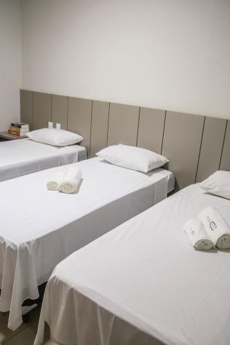 two beds in a room with white sheets at Sttudio One in Araxá
