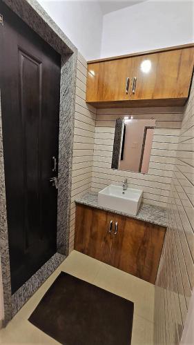 a bathroom with a sink and a black door at Balaji Lodging in Pandharpur