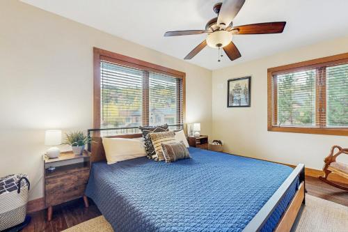 a bedroom with a blue bed with a ceiling fan at Modern Grand Lake Luxury in Grand Lake
