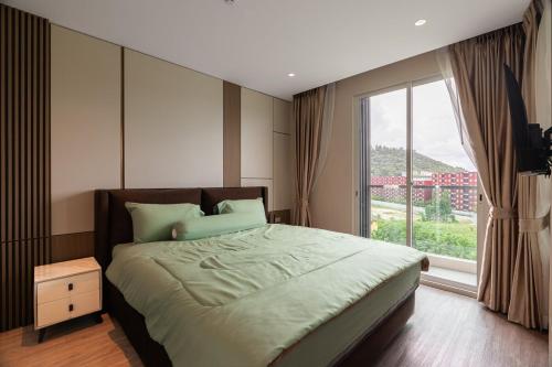 a bedroom with a large bed with a large window at Modern 1BR Condo w Balcony Near Central Phuket in Ban Na Khua