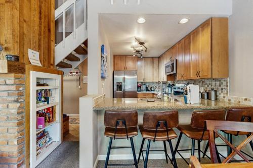 a kitchen with wooden cabinets and a bar with stools at Remodeled 2 Bedroom East Vail Condo 6G with Hot Tub Market Free Shuttle in Vail