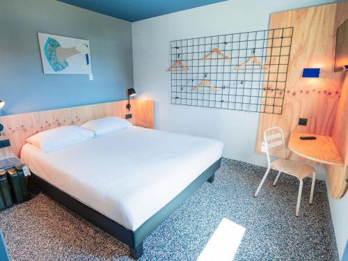 a bedroom with a bed and a table and a chair at Greet hôtel Montpellier Aéroport Parc des Expos in Mauguio
