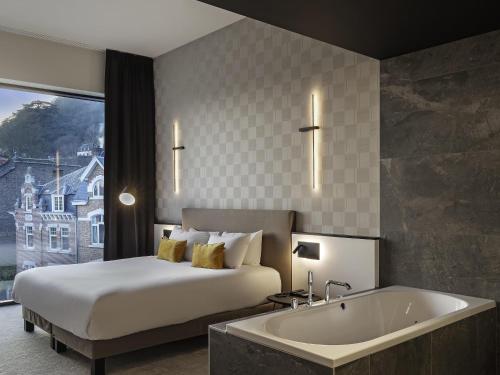 a hotel room with a bed and a bath tub at Mercure Namur Hotel in Namur