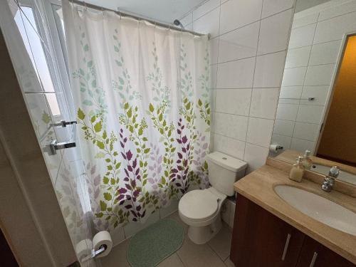a bathroom with a toilet and a shower curtain at Edificio Nueva Trizano in Temuco