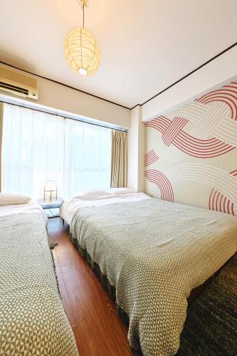 a bedroom with two beds and a large window at 恵比寿駅から徒歩1分 渋谷3分 新宿10分 30m2でゆったり 最高の立地 302号室 in Tokyo