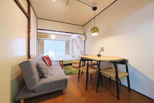 a living room with a couch and a table at 恵比寿駅から徒歩1分 渋谷3分 新宿10分 30m2でゆったり 最高の立地 302号室 in Tokyo